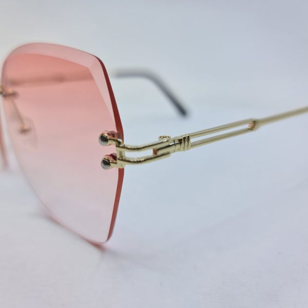 عکس از عینک آفتابی فریم لس پروانه ای با لنز صورتی کم رنگ و دسته طلایی مدل b300