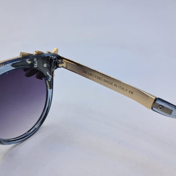 عکس از عینک آفتابی سواروسکی با فریم گرد آبی رنگ و نگین دار و دسته طلایی مدل 6697