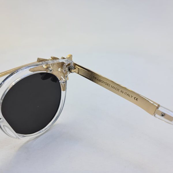 عکس از عینک آفتابی گرد نگین دار با فریم بی رنگ و دسته طلایی برند swarovski مدل 6697