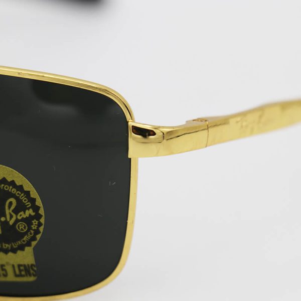 عکس از عینک آفتابی ریبن با فریم طلایی، مستطیلی شکل و لنز سنگ، دودی و آنتی رفلکس مدل am8335