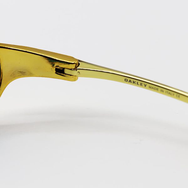 عکس از عینک آفتابی oakley با فریم طلایی رنگ، لنز آینه ای و قرمز رنگ مدل w2239