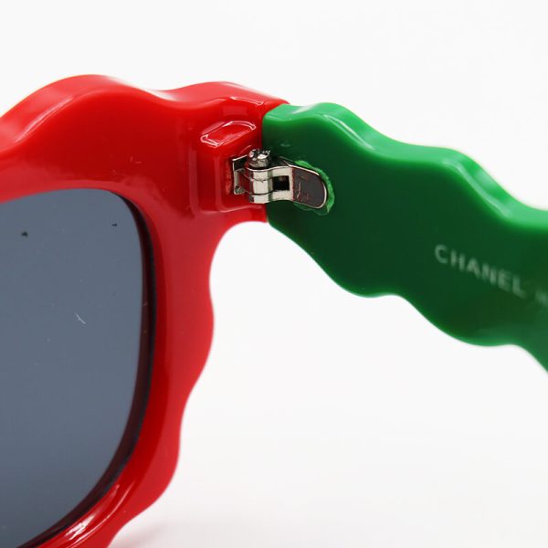 عکس از عینک آفتابی فانتزی زنانه با فریم قرمز رنگ، دسته سبز، ویفرر و لنز دودی شنل مدل fa455