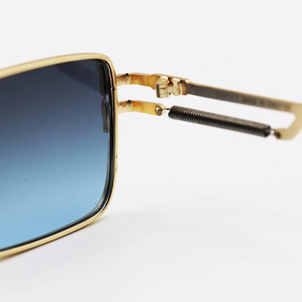 عکس از عینک آفتابی گوچی با فریم طلایی رنگ، مستطیلی شکل، لنز دودی و دسته فنردار مدل fan01