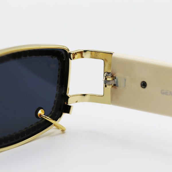 عکس از عینک آفتابی پیرسینگ دار، با فریم نگین دار، طلایی رنگ و دسته کرمی جنتل مانستر مدل gw003