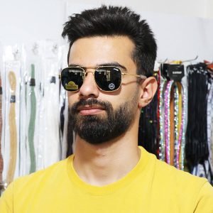 عکس از عینک آفتابی کلاسیک با فریم طلایی رنگ، لنز شیشه ای و رنگ تیره برند راندولف مدل S56 بر روی صورت محمدحسین ابراهیم زاده
