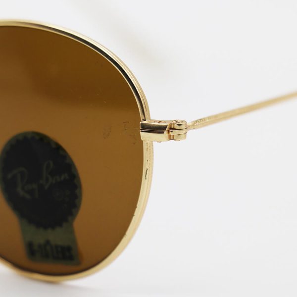 عکس از عینک آفتابی گرد ray-ban با فریم فلزی، طلایی رنگ، عدسی سنگ و قهوه ای تیره مدل 3447