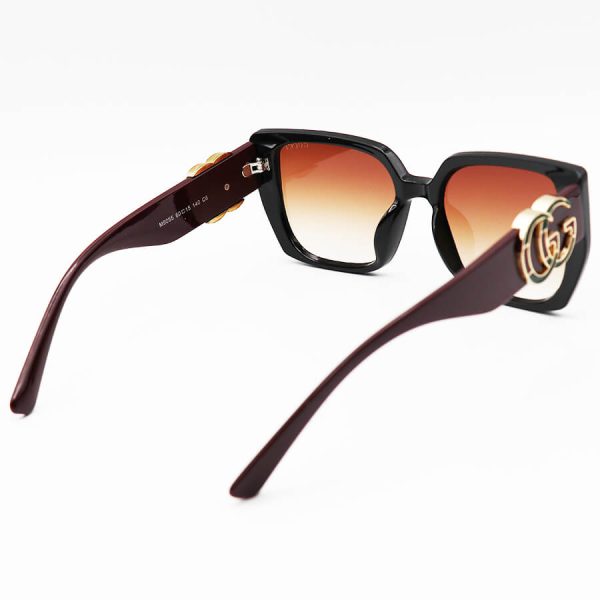 عکس از عینک آفتابی gucci با فریم مشکی رنگ، پروانه ای شکل، دسته زرشکی و لنز قهوه ای مدل m9055