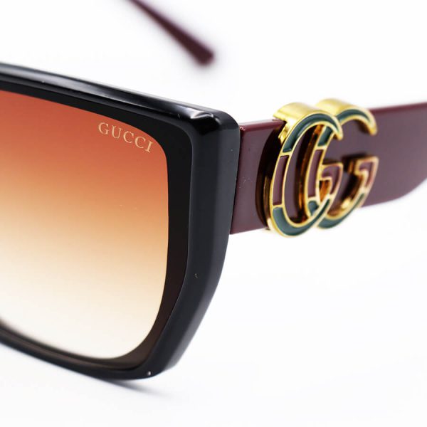 عکس از عینک آفتابی gucci با فریم مشکی رنگ، پروانه ای شکل، دسته زرشکی و لنز قهوه ای مدل m9055