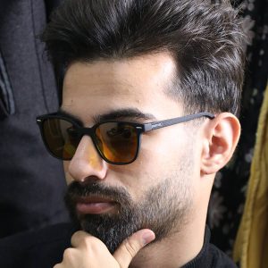 عکس از عینک دید در شب اوگا مورل با فریم مشکی مات، مربعی شکل، دسته فنری و لنز زرد رنگ مدل 78011 بر روی صورت محمدحسین ابراهیم زاده