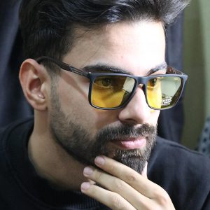 عکس از عینک شب Diesel با فریم مربعی، مشکی مات، دسته چوبی، رنگ قهوه‌ای و لنز پلاریزه و زرد رنگ مدل P5306 بر روی صورت محمدحسین ابراهیم زاده