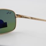 عکس از عینک آفتابی Ray-Ban با فریم طلایی مات، شکل خلبانی و لنز سبز تیره و از جنس شیشه مدل RB3317