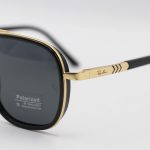 عکس از عینک آفتابی Ray-Ban با فریم مشکی و طلایی، شکل چند ضلعی، دسته فنری و لنز دودی تیره و پلاریزه مدل P9004