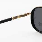 عکس از عینک آفتابی Ray-Ban با فریم مشکی و طلایی، شکل چند ضلعی، دسته فنری و لنز دودی تیره و پلاریزه مدل P9004