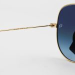 عکس از عینک آفتابی Ray-Ban با فریم خلبانی، رنگ طلایی، لنز از جنس سنگ، آبی تیره و هایلایت مدل RB3026 HQ