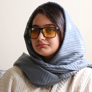عکس از عینک دید در شب Police با فریم مستطیلی شکل، رنگ مشکی مات و لنز زرد رنگ مدل H1024 بر روی صورت فاطمه ابراهیم زاده