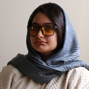 عکس از عینک شب پورشه دیزاین با فریم مستطیلی شکل، رنگ مشکی مات، دسته فنردار و لنز زرد رنگ مدل 1082 بر روی صورت فاطمه ابراهیم زاده