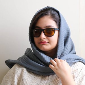 عکس از عینک شب اوگا مورل با فریم مشکی مات، مستطیلی شکل، بیس‌دار و دسته فنری و لنز زرد رنگ مدل 78068 بر روی صورت فاطمه ابراهیم زاده