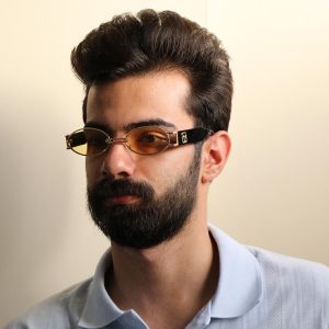 عکس از عینک دید در شب جنتل مانستر با فریم طلایی رنگ، بیضی شکل و دسته مشکی و لنز زرد رنگ مدل B2069 بر روی صورت محمدحسین ابراهیم زاده